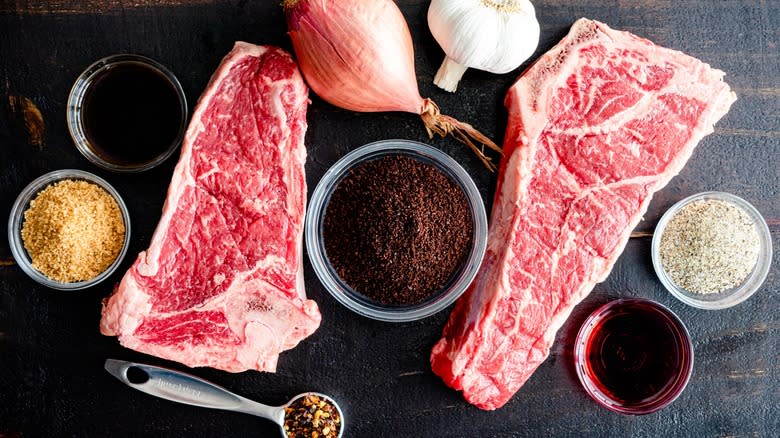 Top-down view of raw steaks with cocoa powder and aromatics