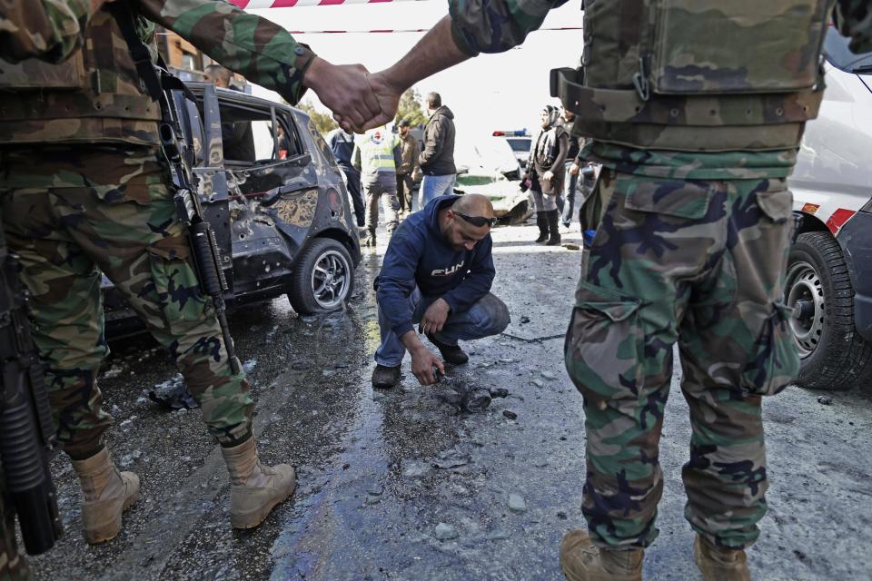 Lebanese army investigators work at the site of an explosion, in the suburb of Beir Hassan, Beirut, Lebanon, Wednesday, Feb. 19, 2014. Two suicide bombers blew up their cars Wednesday trying to hit an Iranian cultural center in a Shiite district in southern Beirut, killing at least four people and wounding more than a hundred, according to Lebanese officials and an al-Qaida linked group that claimed responsibility. (AP Photo/Hassan Ammar)