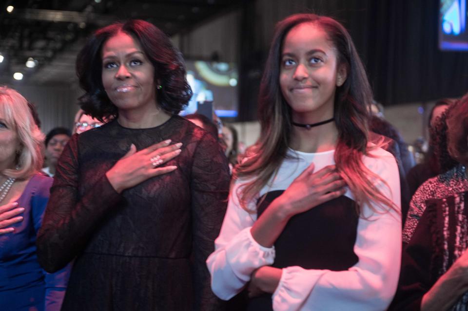 US First Lady Michelle Obama and daughter Malia listen to the national anthem before President Barack Obama delivers his farewell address in Chicago, Illinois in 2017. (Photo: NICHOLAS KAMM/AFP/Getty Images)