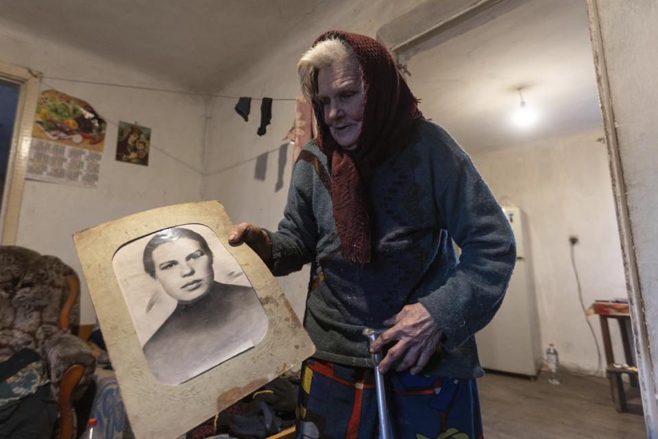 Halyna Moroka holds a portrait of her younger self in her house in the village of Nevelske in eastern Ukraine, Friday, Dec. 10, 2021. The 7-year-old conflict between Russia-backed separatists and Ukrainian forces has all but emptied the village. “We have grown accustomed to the shelling,” said Moroka, 84, who has stayed in Nevelske with her disabled son. (AP Photo/Andriy Dubchak)