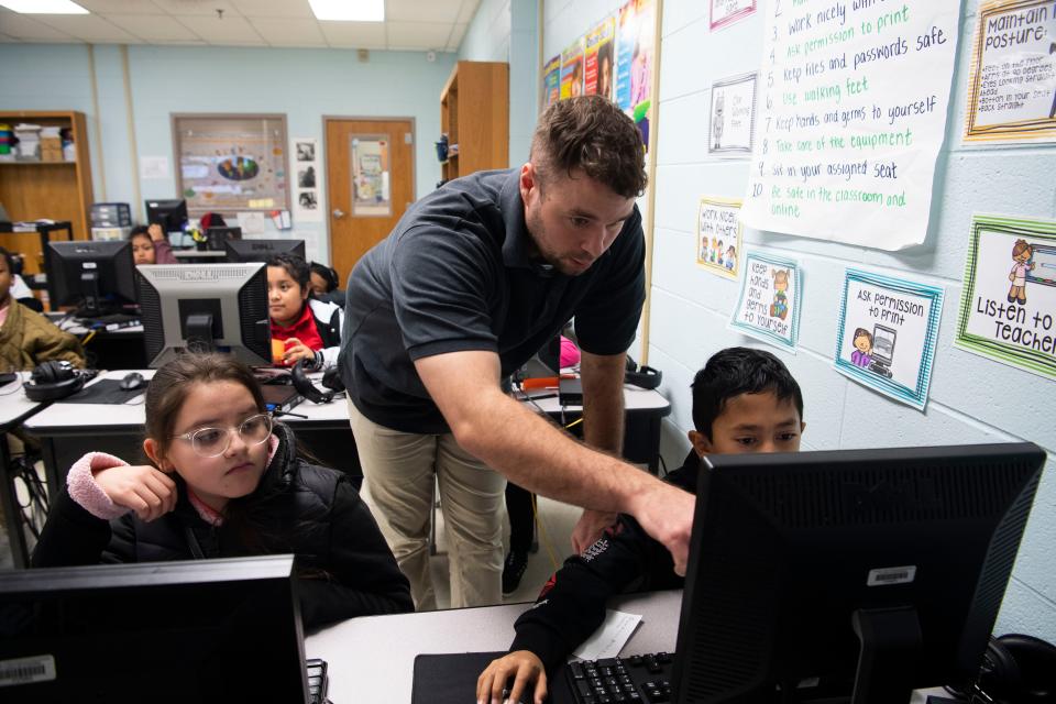 Anson Amour helps a student at Tom Joy Elementary School in Nashville , Tenn., Monday, Nov. 28, 2022.