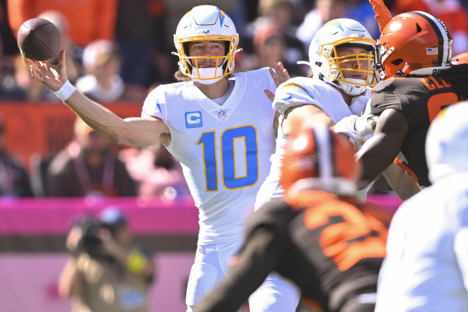 Los Angeles Chargers quarterback Justin Herbert (10) passes as the Los Angeles Chargers defense looks to pressure him during the first half of an NFL football game, Sunday, Oct. 9, 2022, in Cleveland. (AP Photo/David Richard)