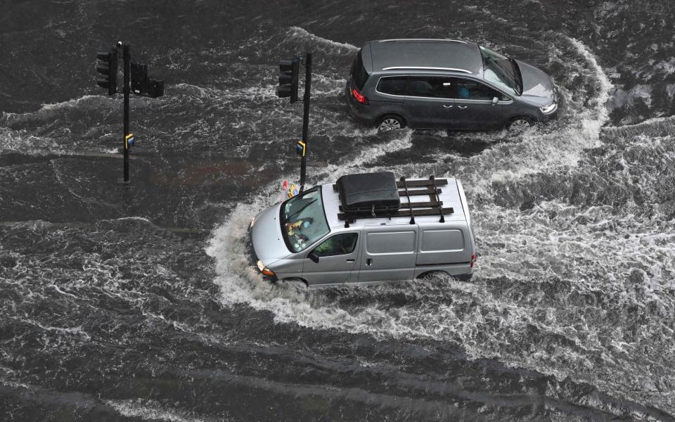 Vehicles drive through deep water on a flooded road in The Nine Elms district of London - JUSTIN TALLIS 