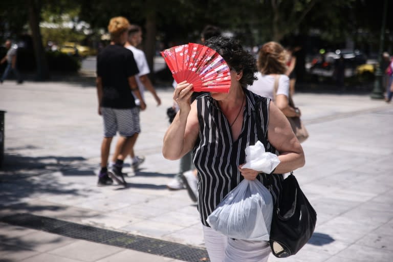 Una transeúnte se protege del sol con un abanico el 10 de julio de 2024 en la Plaza Syntagma de Atenas (Aris Oikonomou)