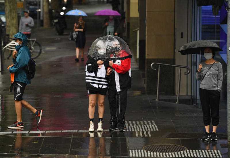 People are seen using an umbrella in the rain in Melbourne.