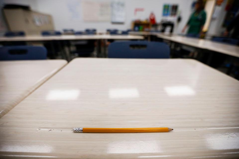 A pencil on a desk in a classroom.
