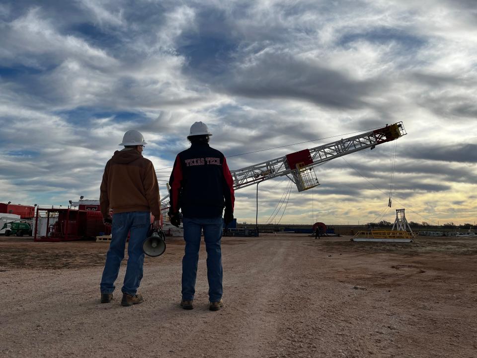 (left) Danny Bullard and Marshal Watson watching the 140-foot mast of the first operational oil rig on a university campus in the nation being raised on the Texas Tech campus.