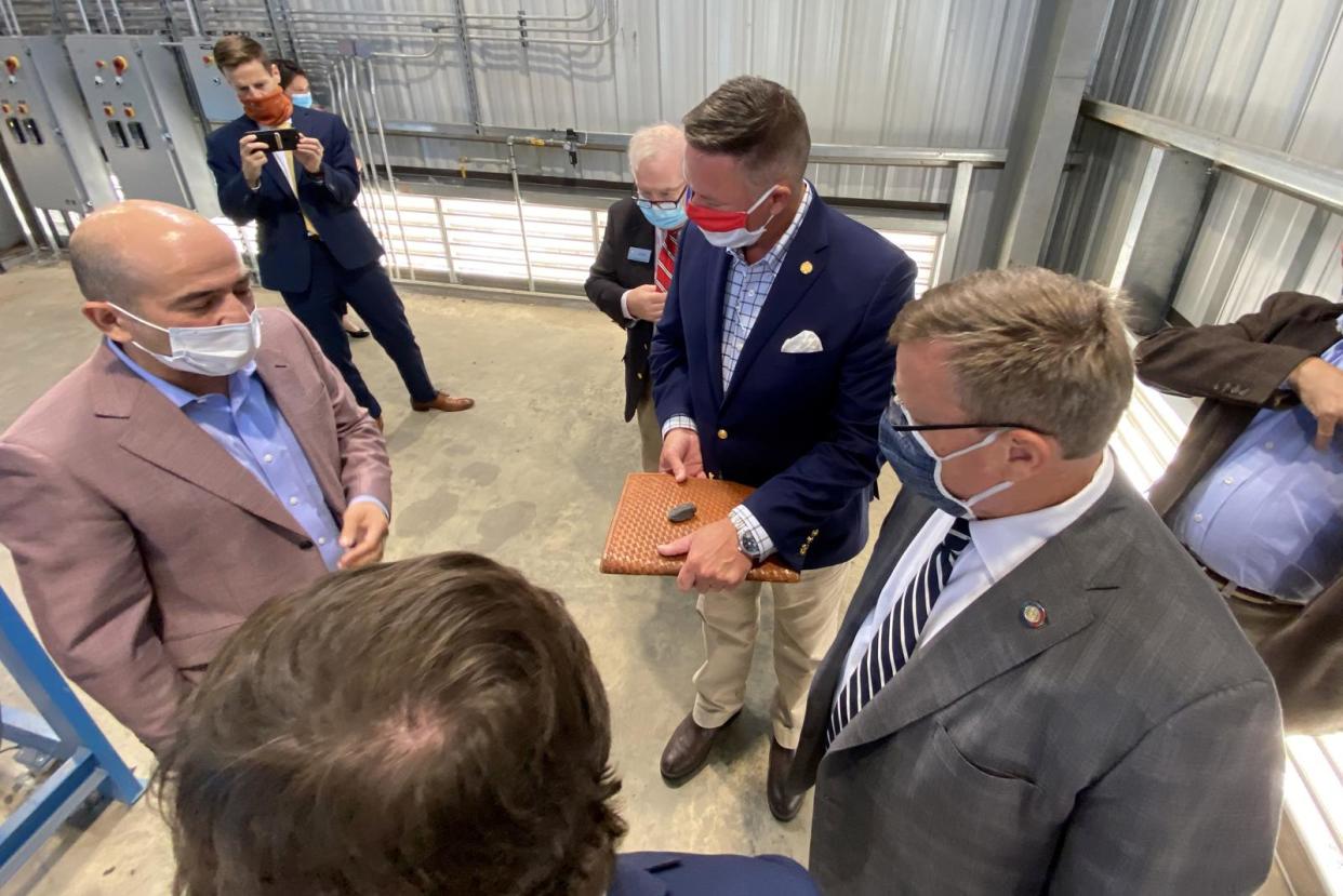 Mike Levine, CEO of Mafic, shows Tim Moore and Robert Hosford what kind of rocks the plant melts down to make fibers in this Star file photo.