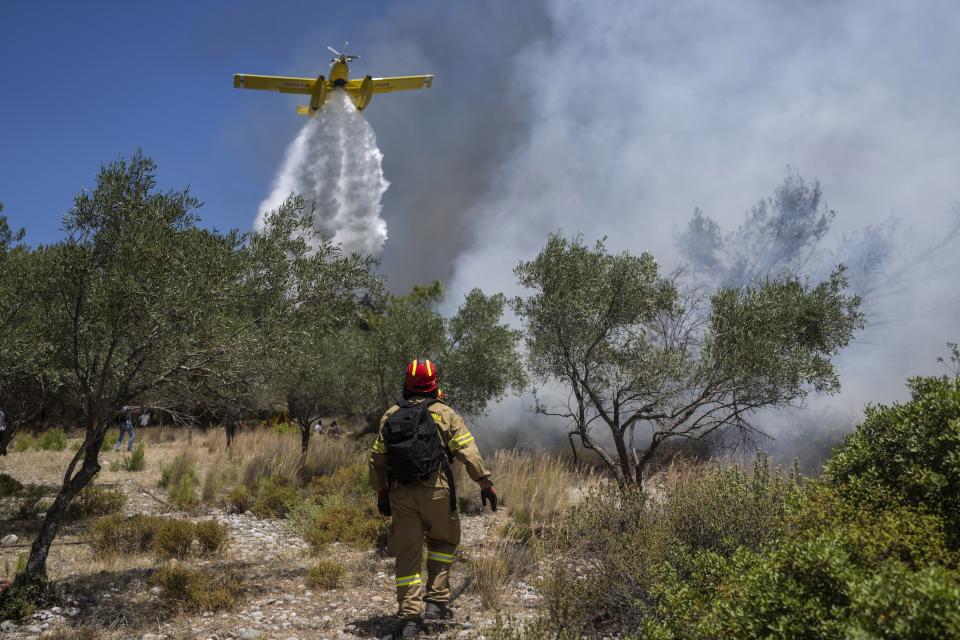 An aircraft drops water over a wildfire in Vati village, on the Aegean Sea island of Rhodes, southeastern Greece, on Tuesday, July 25, 2023. A third successive heat wave in Greece pushed temperatures back above 40 degrees Celsius (104 degrees Fahrenheit) across parts of the country Tuesday following more nighttime evacuations from fires that have raged out of control for days. (AP Photo/Petros Giannakouris)