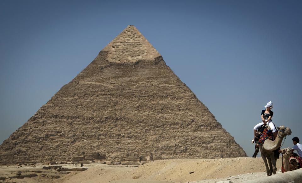 In this Thursday, Sept. 27, 2012 photo, a foreign tourist enjoys a ride on a camel as she visits the historical site of the Giza Pyramids, near Cairo, Egypt. The Egyptian demonstrations against an online film that was produced by a U.S. citizen originally from Egypt and denigrates the Prophet Muhammad were part of a wider explosion of anger in Muslim countries. They happened near the U.S. Embassy, far from the pyramids of Giza on Cairo's outskirts, and a lot further from gated Red Sea resorts, cocoons for the beach-bound vacationer. Yet the online or TV images _ flames, barricades, whooping demonstrators _ are a killjoy for anyone planning a getaway, even though the protests have largely subsided. Tour guides in Egypt say tourist bookings are mostly holding, but they worry about a dropoff early next year, since people tend to plan several months ahead.(AP Photo/Khalil Hamra)