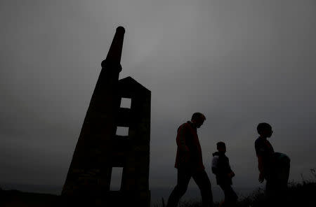 FILE PHOTO: A family walk past the remains of the engine house at the Wheal Prosper copper and tin mine, on the Cornish coastline near Porthleven in Cornwall, Britain October 26, 2017. REUTERS/Toby Melville/File Photo