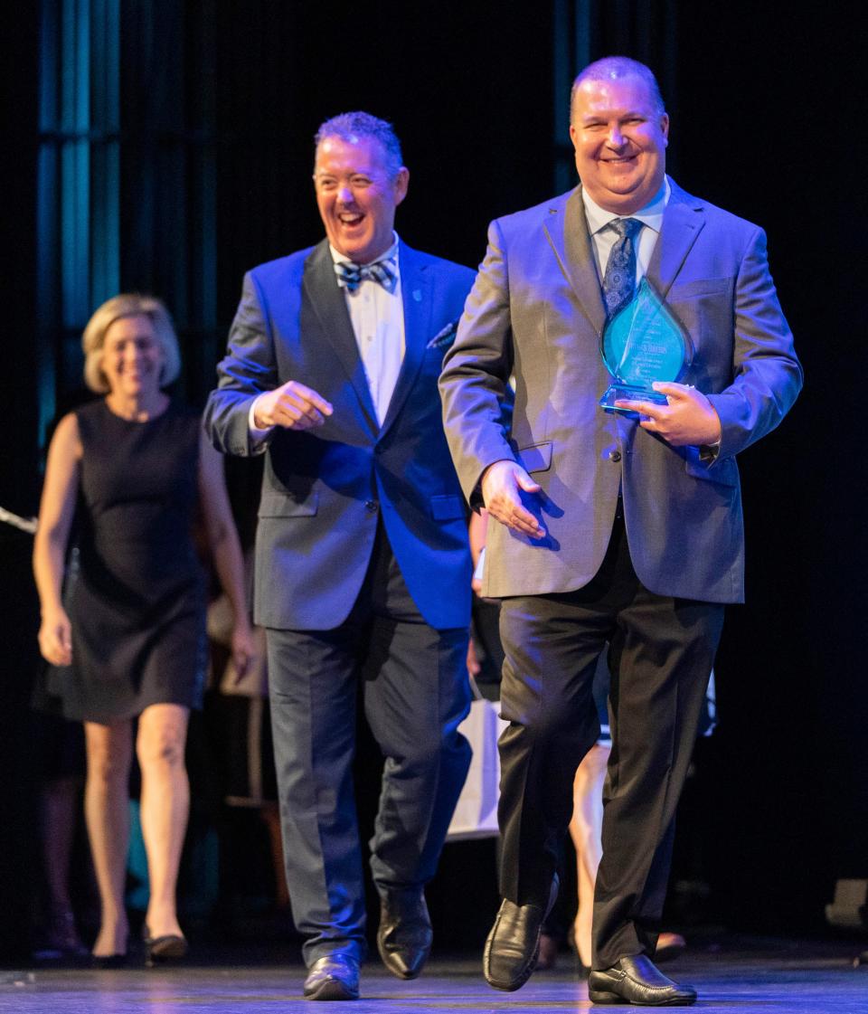 Pioneer Park Elementary teacher Thomas Hrebin, right, was presented theÊwon the Dwyer Award for Excellence in Education for Student Advancement and Career Education by UnitedHealthCar's  Jim Moore, center, during a ceremony at the Kravis Center on May 1, 2023 in West Palm Beach, Florida.