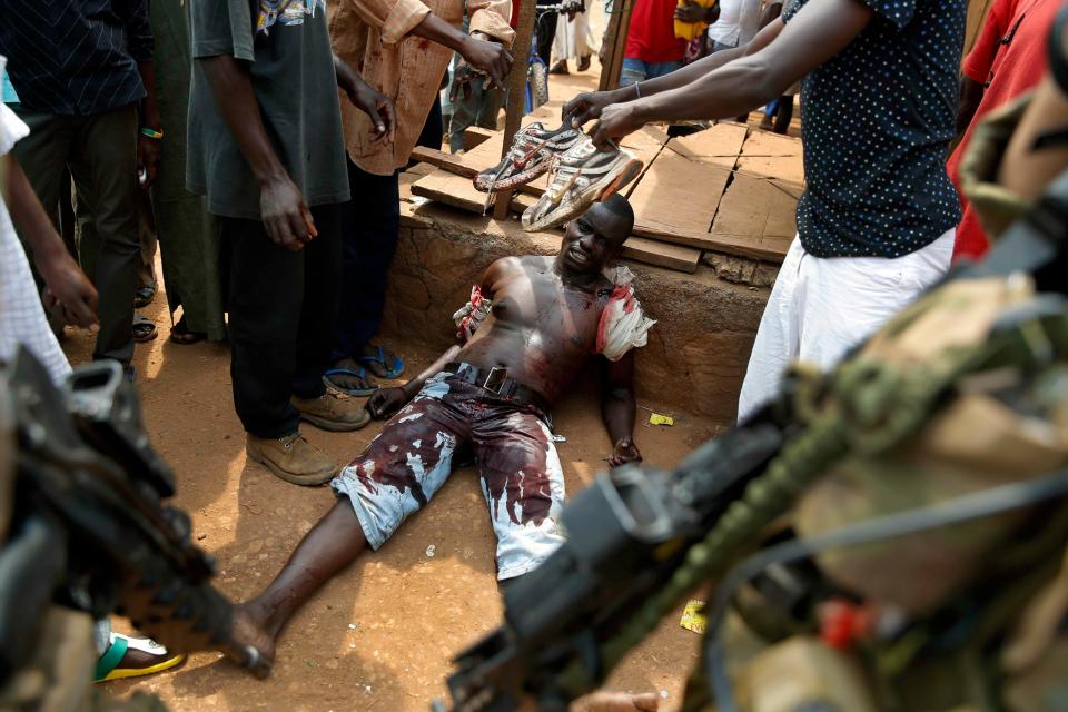 FILE - In this Monday, Dec. 9, 2013 file photo, a suspected member of a Christian militia Sincere Banyodi, 32, lays wounded by machete blows in the Kokoro neighborhood of Bangui, Central African Republic. Sub-Saharan Africa has seen a very violent start to 2014 with raging conflicts in South Sudan and Central African Republic - the death tolls are huge and the individual incidents gruesome, with one estimate saying nearly 10,000 have been killed in South Sudan in a month of warfare. (AP Photo/Jerome Delay, File)