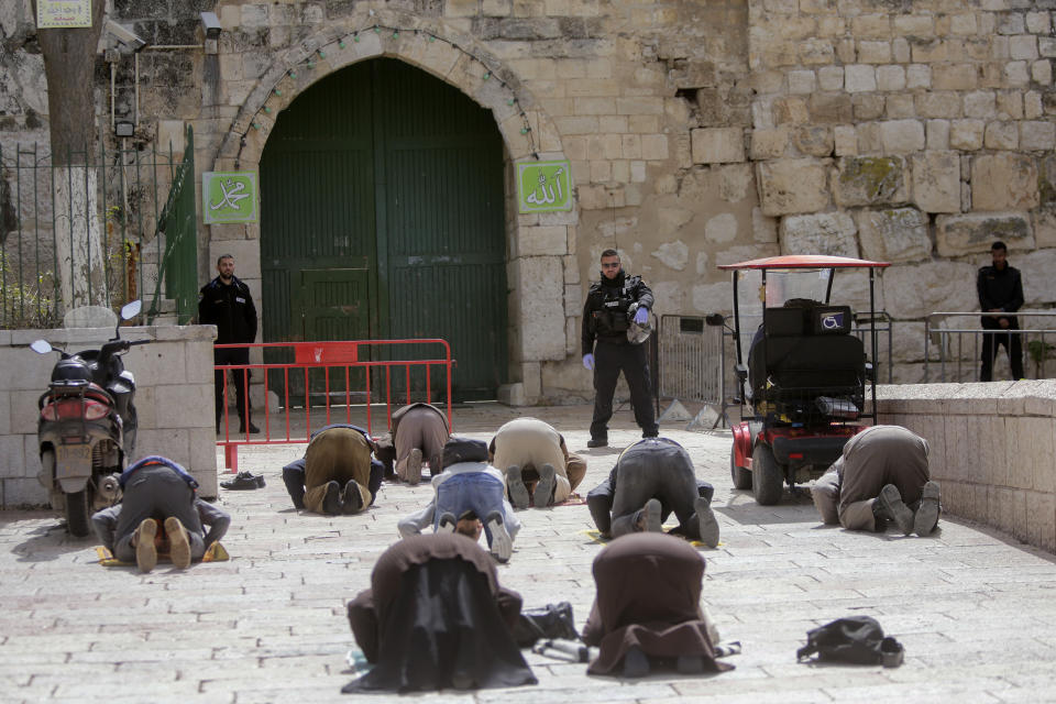 People pray in front of the shuttered gates to al-Aqsa mosque compound as all prayers are suspended to prevent the spread of coronavirus in Jerusalem, Monday, March 23, 2020. In Israel daily life has largely shut down with coronavirus cases multiplying greatly over the past week, (AP Photo/Mahmoud Illean)