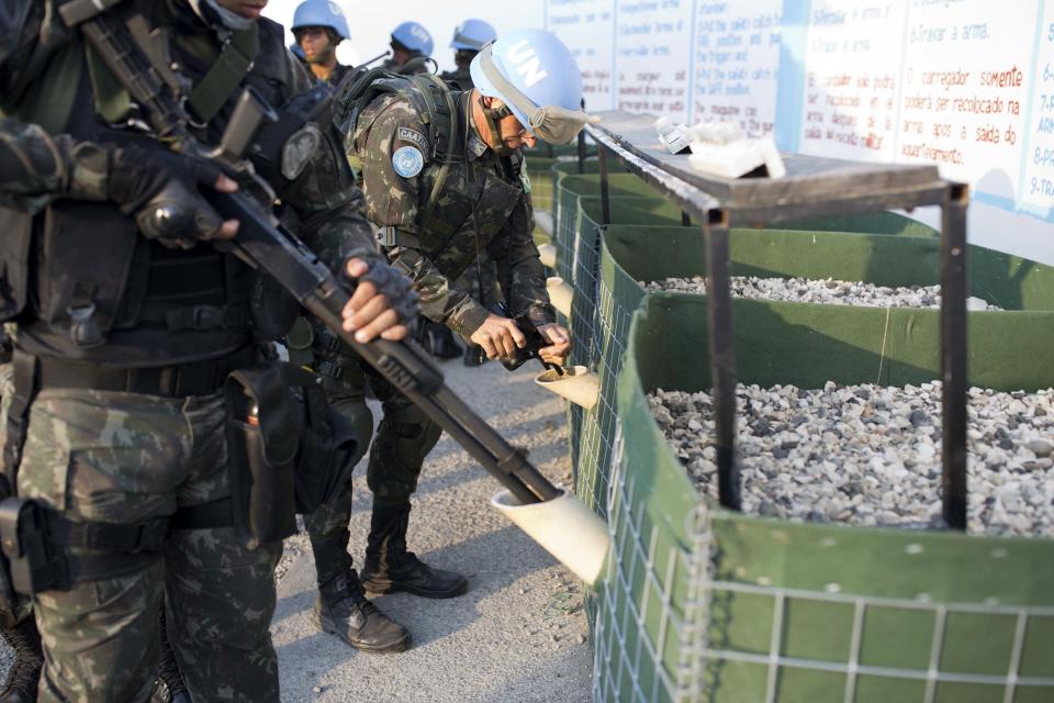 In this Feb. 22, 2017 photo, U.N. peacekeepers from Brazil discharge their guns in a weapon unloading area after patrolling in the Cite Soleil slum, in Port-au-Prince, Haiti. Washington, the Haiti mission's penholder, is applying pressure to wind up peacekeeping operations that cost $346 million a year. (AP Photo/Dieu Nalio Chery)