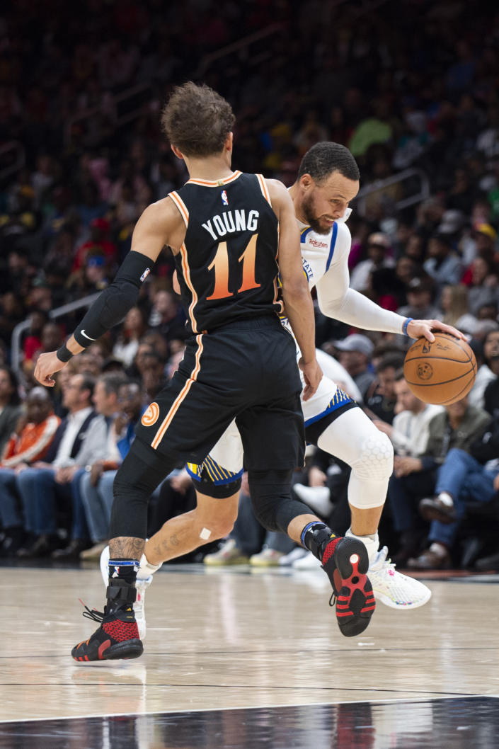 Golden State Warriors guard Stephen Curry, right, drives against Atlanta Hawks guard Trae Young during the first half of an NBA basketball game, Friday, March 17, 2023, in Atlanta. (AP Photo/Hakim Wright Sr.)