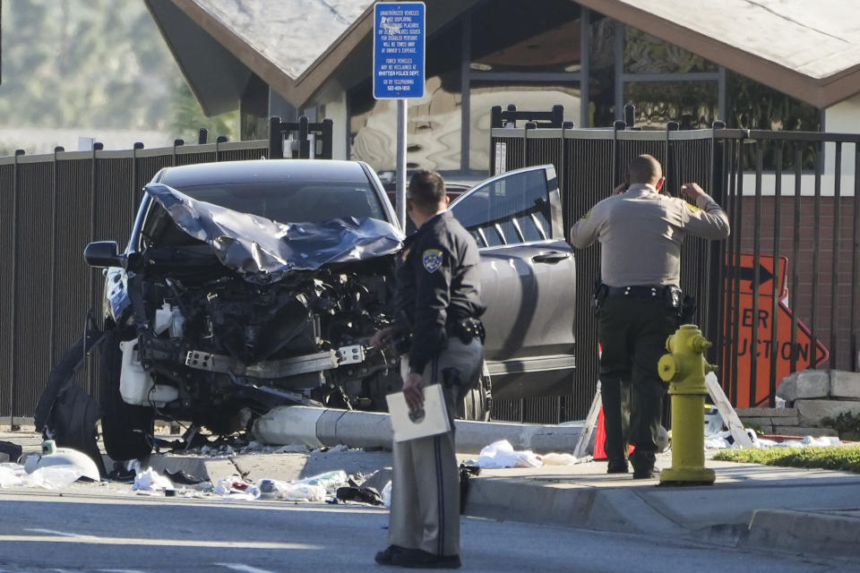 Two investigators stand next to a mangled SUV that struck Los Angeles County sheriff's recruits in Whittier, Calif., Wednesday, Nov. 16, 2022. The vehicle struck several Los Angeles County sheriff's recruits on a training run around dawn Wednesday, some were critically injured, authorities said. (AP Photo/Jae C. Hong)