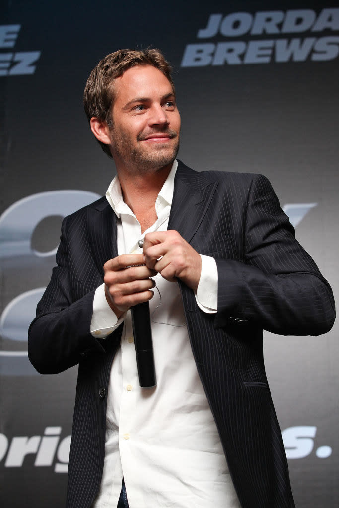 Paul Walker smiling and holding a mic