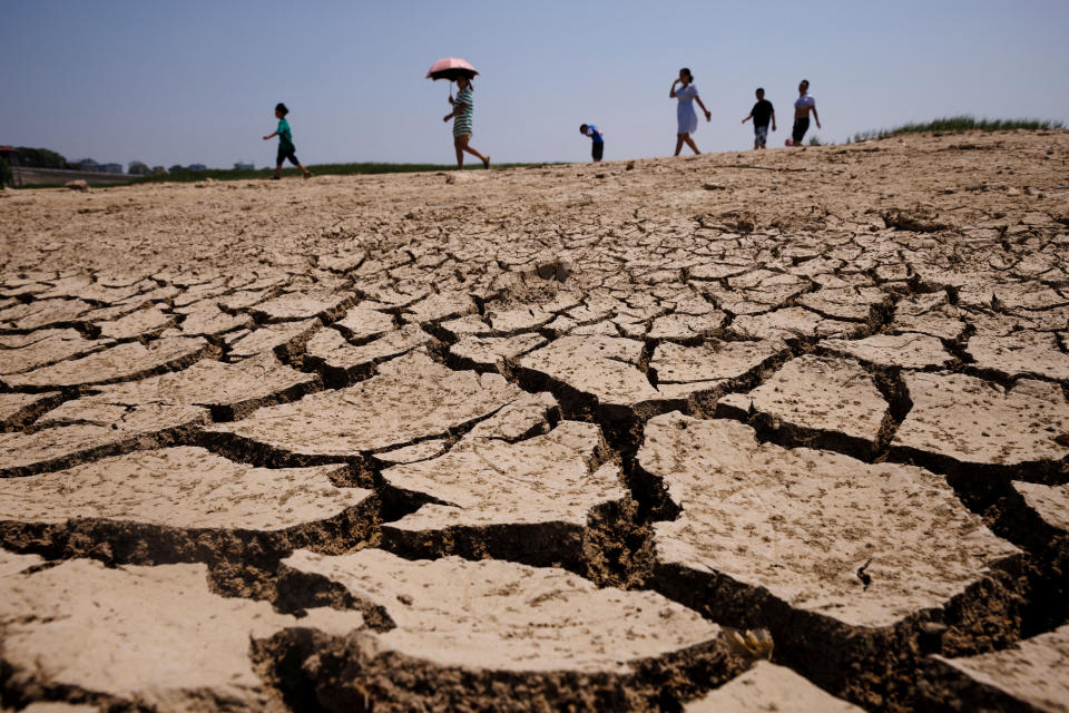 People walk across a dried-up section of Poyang Lake that is facing low water levels due to a regional drought in Lushan, Jiangxi province, China, August 24, 2022.  REUTERS/Thomas Peter