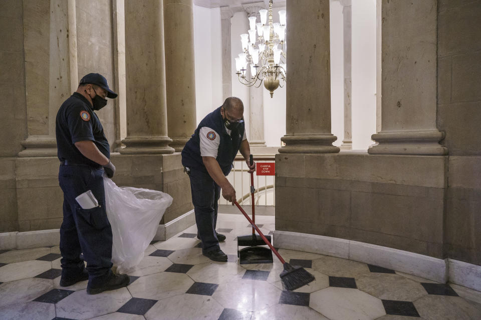 Workmen clean up debris outside the office of Speaker of the House Nancy Pelosi on the day after violent protesters loyal to President Donald Trump stormed the U.S. Congress, at the Capitol in Washington, Thursday, Jan. 7, 2021. (AP Photo/J. Scott Applewhite)