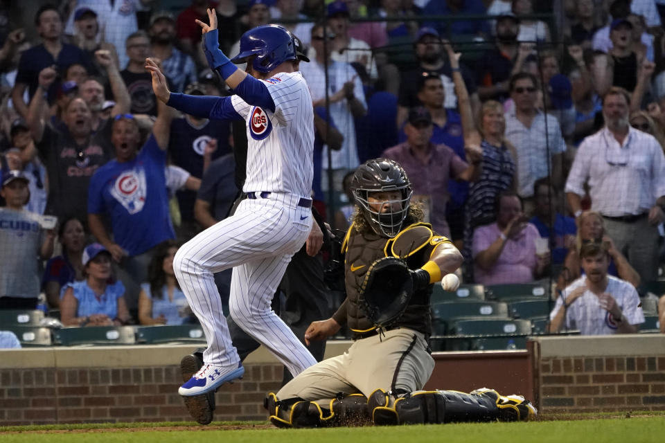 Chicago Cubs' Ian Happ, left, scores behind San Diego Padres catcher Jorge Alfaro on a triple by Nico Hoerner during the fourth inning of a baseball game Tuesday, June 14, 2022, in Chicago. (AP Photo/Charles Rex Arbogast)