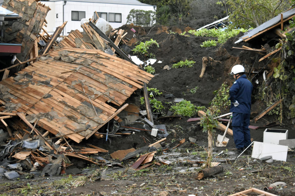 A police officer looks at a house damaged by Typhoon Hagibis, in Tomioka, north of Tokyo, Sunday, Oct. 13, 2019. Rescue efforts for people stranded in flooded areas are in full force after a powerful typhoon dashed heavy rainfall and winds through a widespread area of Japan, including Tokyo.(Kyodo News via AP)