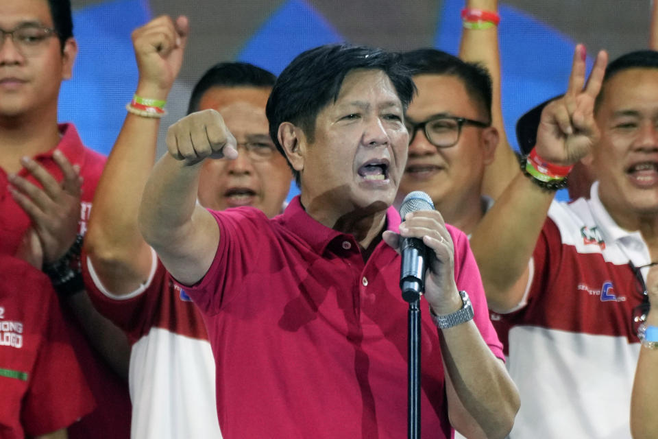 Presidential hopeful Ferdinand Marcos Jr in red shirt holding a mic speaking before the crowd at his campaign rally.