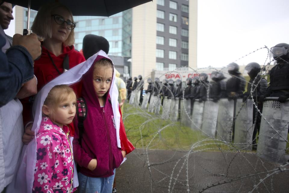 FILE - In this Sunday, Sept. 6, 2020 file photo, people with their children stand at a barbed wire fence in front of a police line toward the Independence Palace, residence of the President Alexander Lukashenko, during Belarusian opposition supporters rally in Minsk, Belarus. Belarus President Alexander Lukashenko has relied on massive arrests and intimidation tactics to hold on to power despite nearly three months of protests sparked by his re-election to a sixth term, but continuing protests have cast an unprecedented challenge to his 26-year rule. (AP Photo/TUT.by, File)