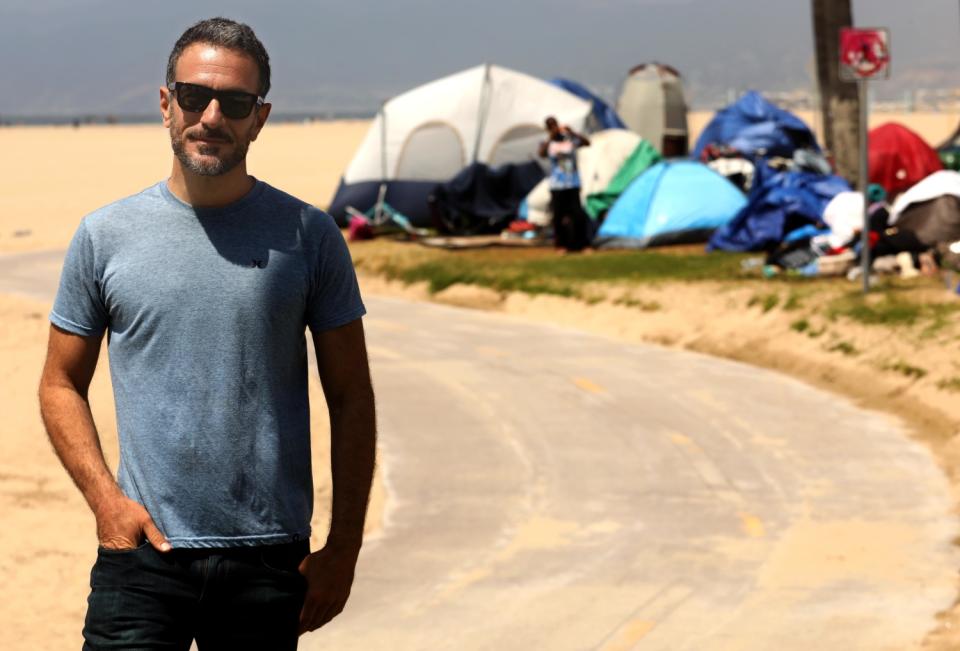 Brian Averill stands in front of a homeless camp