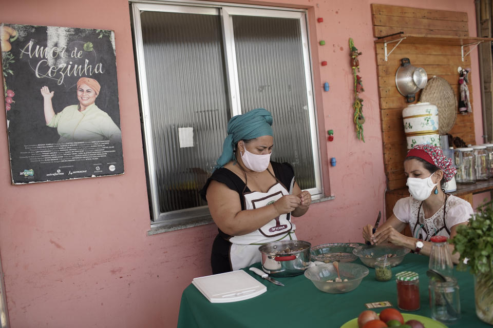 Chef Regina Tchelly, left, and director of the Hand in the Jackfruit organization Marisa Furtado, peel jackfruit seeds at the culinary project Favela Organica run by Tchelly, in the Babilonia favela of Rio de Janeiro, Brazil, Thursday, Feb. 11, 2021. Tchelly said she believes jackfruit could end Brazilian hunger. (AP Photo/Silvia Izquierdo)