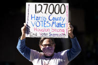 FILE - In this Nov. 2, 2020, file photo, demonstrator Gina Dusterhoft holds up a sign as she walks to join others standing across the street from the federal courthouse in Houston, before a hearing in federal court involving drive-thru ballots cast in Harris County. In 2020, election officials in Harris County, Texas, which includes the Democratic stronghold of Houston and is one of the most racially diverse in the nation, went further than anywhere else in the state to create new ways to vote. (AP Photo/David J. Phillip, File)