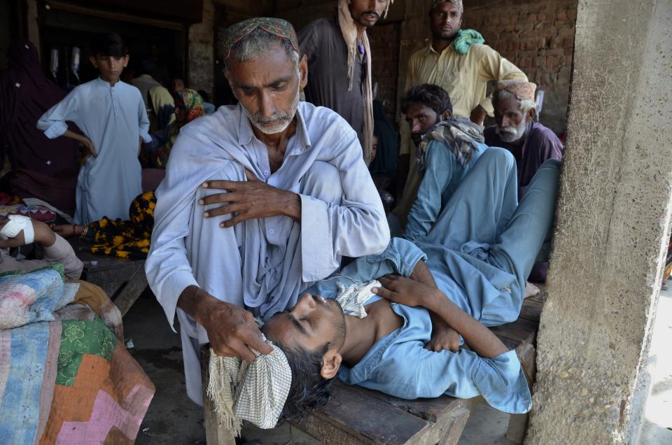 A man takes care of his sick son receiving treatment at a temporary medical center setup in abandoned building, in Jaffarabad, a flood-hit district of Baluchistan province, Pakistan, Thursday, Sept. 15, 2022. The devastating floods affected over 33 million people and displaced over half a million people who are still living in tents and make-shift homes. The water has destroyed 70% of wheat, cotton and other crops in Pakistan. (AP Photo/Zahid Hussain)