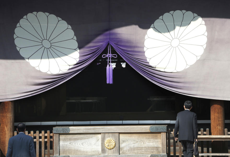 FILE - In this April 23, 2013 file photo, a group of Japanese lawmakers, seen silhouetted in the middle of the photo, offer prayers at the Yasukuni Shrine, which honors Japan's war dead, including World War II leaders convicted of war crimes, in Tokyo during an annual spring festival. A Japanese Cabinet minister visited the Tokyo shrine that honors the dead including war criminals in what has repeatedly caused friction with Japan's neighbors. Lawmaker Keiji Furuya, who chairs the National Public Safety Commission, said on his website that he paid respects Sunday morning, April 20, 2014, at the Yasukuni shrine ahead of a festival that starts Monday.(AP Photo/Koji Sasahara, File)