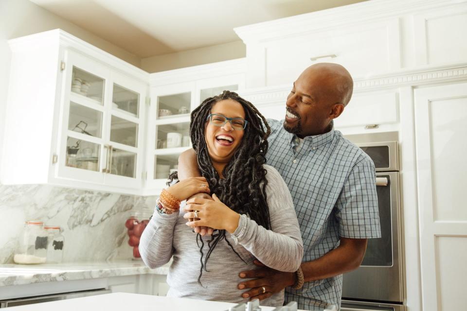 smiling man embracing female partner in kitchen at home