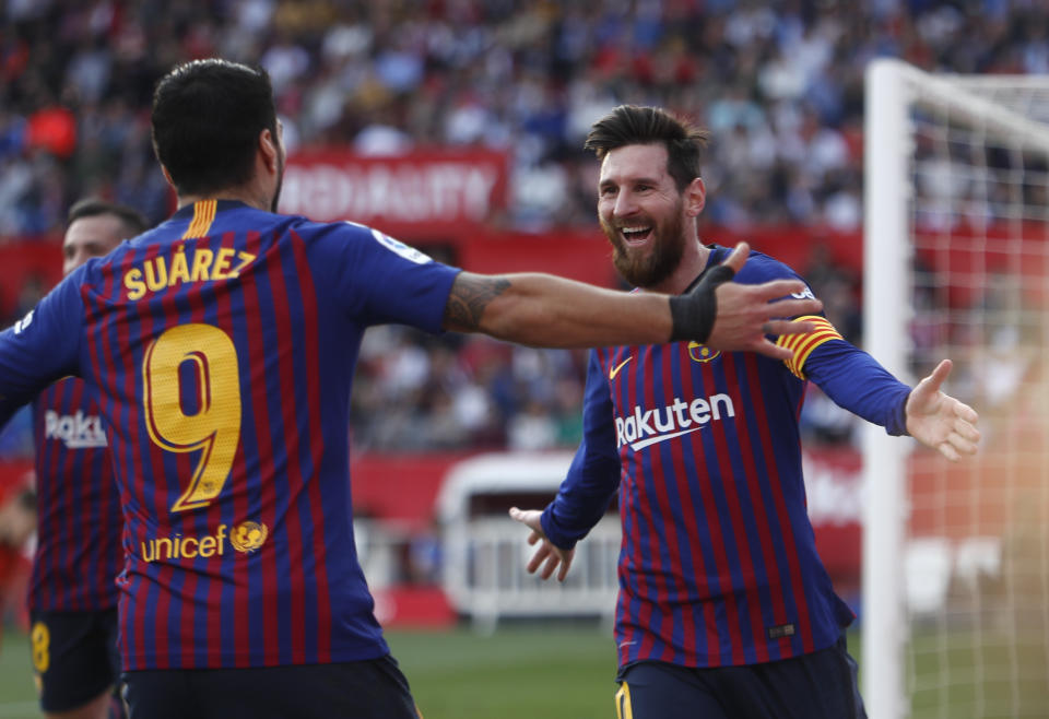 Lionel Messi festeja con su compañero Luis Suárez tras anotar su tercer gol en el partido de la Liga española, en Sevilla, el sábado 23 de febrero de 2019. (AP Foto/Miguel Morenatti)