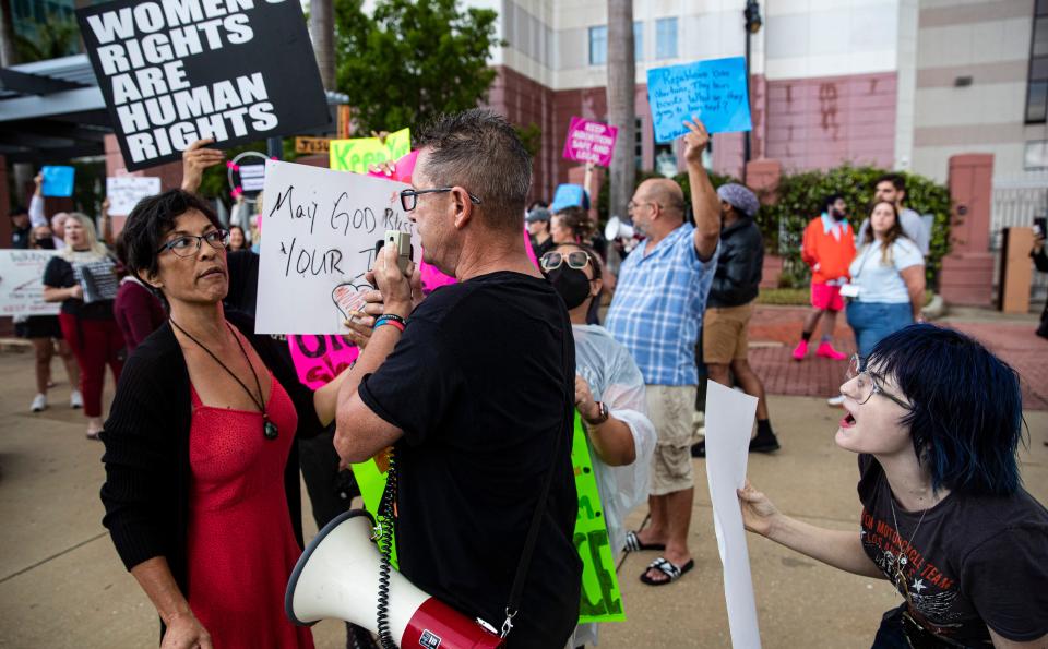 Pro-choice protesters, Jaime Renee Cruz, left,  and Addyson Ryan, right,  have a heated conversation with anti abortion protester, Tom Cabral, center, during a protest in downtown Fort Myers on Tuesday. Supporters and opponents of abortion rights were present. Members for abortion rights held the protest in response to a leaked draft opinion from the Supreme Court seeking to overturn Roe v. Wade. 