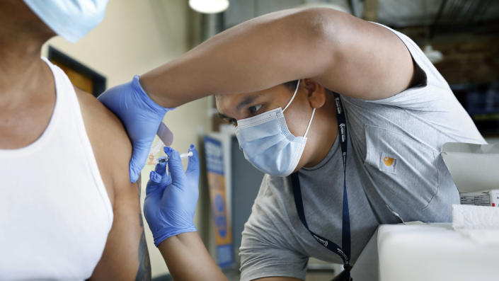 Registered nurse Jeremy Oyague administers a COVID booster shot to a patient.