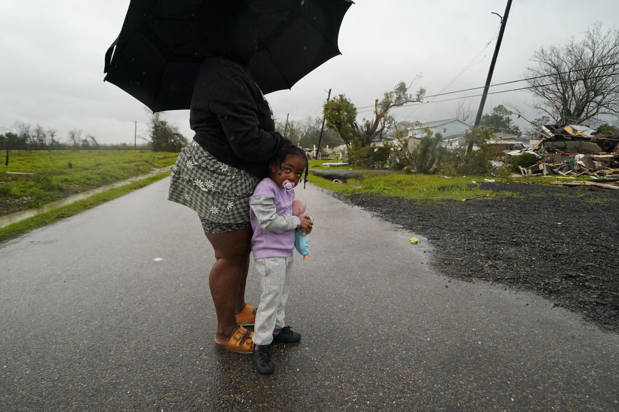 Trinity Allen, 4, stands in the rain with her grandmother after they came to help friends whose home was destroyed from a tornado that tore through the area in Killona, La., about 30 miles west of New Orleans in St. James Parish, Wednesday, Dec. 14, 2022. (AP Photo/Gerald Herbert)