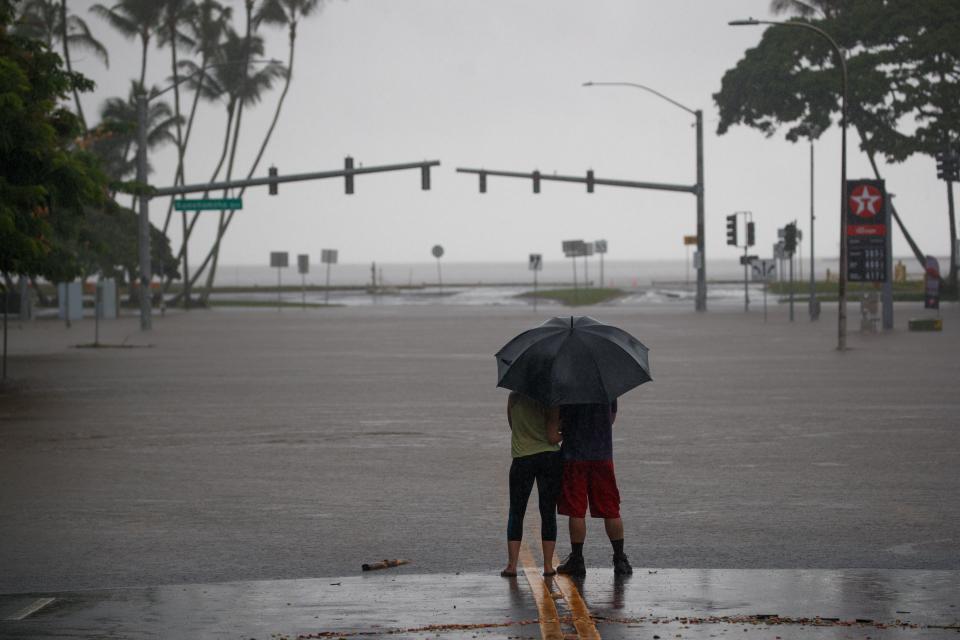 <p>Michelle Montgomery (L) and Eric Leifer (R) share a moment under an umbrella, as they view the flooded Pauahi St and Kamehameha Ave intersection in Hilo, Hawaii, Aug. 24, 2018. (Photo: Bruce Omori/EPA-EFE/REX/Shutterstock) </p>