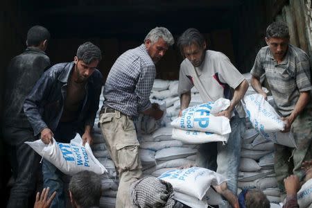 Men unload flour from a Red Crescent and United Nations aid convoy in the rebel held besieged town of Hamoria area, in the eastern suburbs of Damascus, Syria, April 19, 2016. REUTERS/Bassam Khabieh