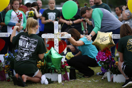 Mourners pray at a makeshift memorial left in memory of the victims killed in a shooting at Santa Fe High School in Santa Fe, Texas, U.S., May 21, 2018. REUTERS/Jonathan Bachman