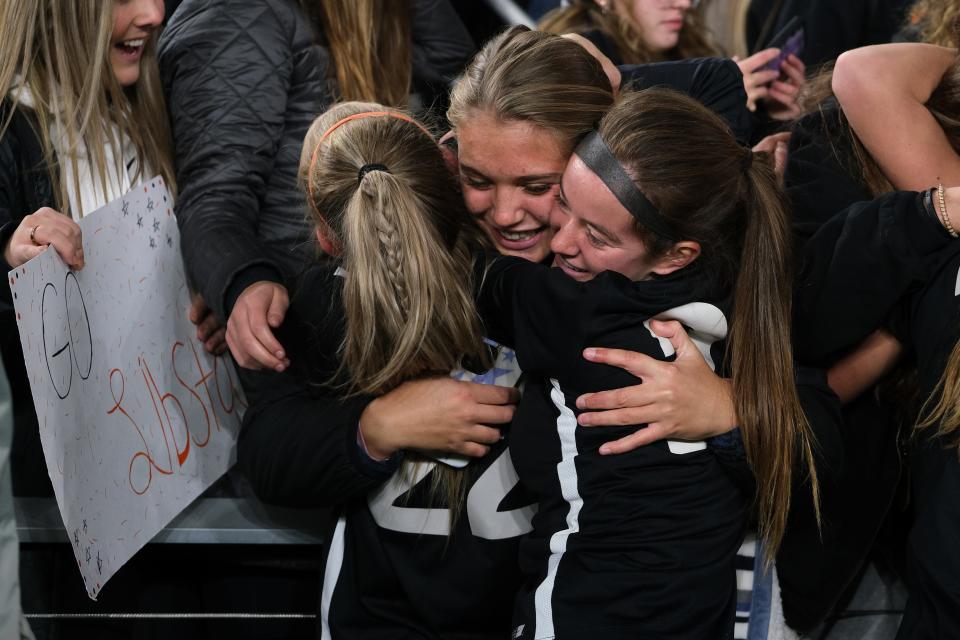 Waynesville midfielder Libby Bulach (22) and teammate defender Kate Handle (2) celebrate with a spectator after winning the OHSAA girls Division III state soccer championship against Ottawa-Glendorf at Lower.com Field in Columbus, Ohio, Friday, Nov. 12, 2021.