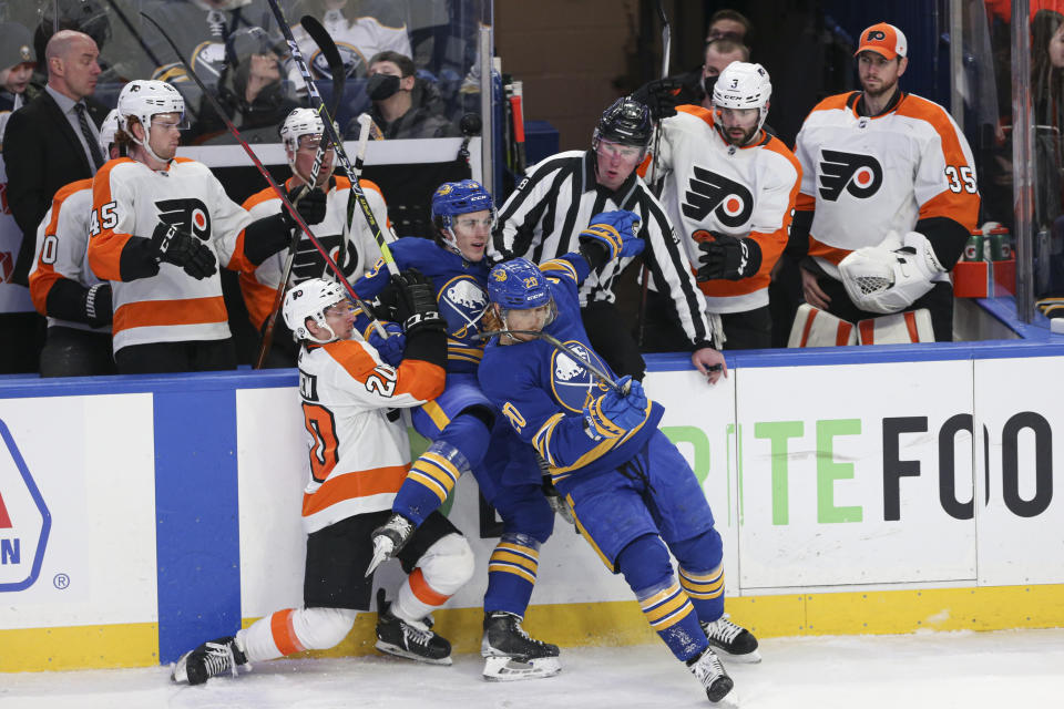 Philadelphia Flyers center Gerry Mayhew (20) checks Buffalo Sabres center Peyton Krebs (19) into center Cody Eakin (20) during the third period of an NHL hockey game Saturday, Jan. 22, 2022, in Buffalo, N.Y. (AP Photo/Joshua Bessex)