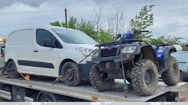 A quad bike and a white van on a tow truck
