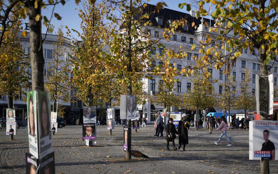 People pass by election campaign posters in Copenhagen, Denmark, Sunday, Oct. 30, 2022, ahead of the general election on November 1, 2022. (AP Photo/Sergei Grits)