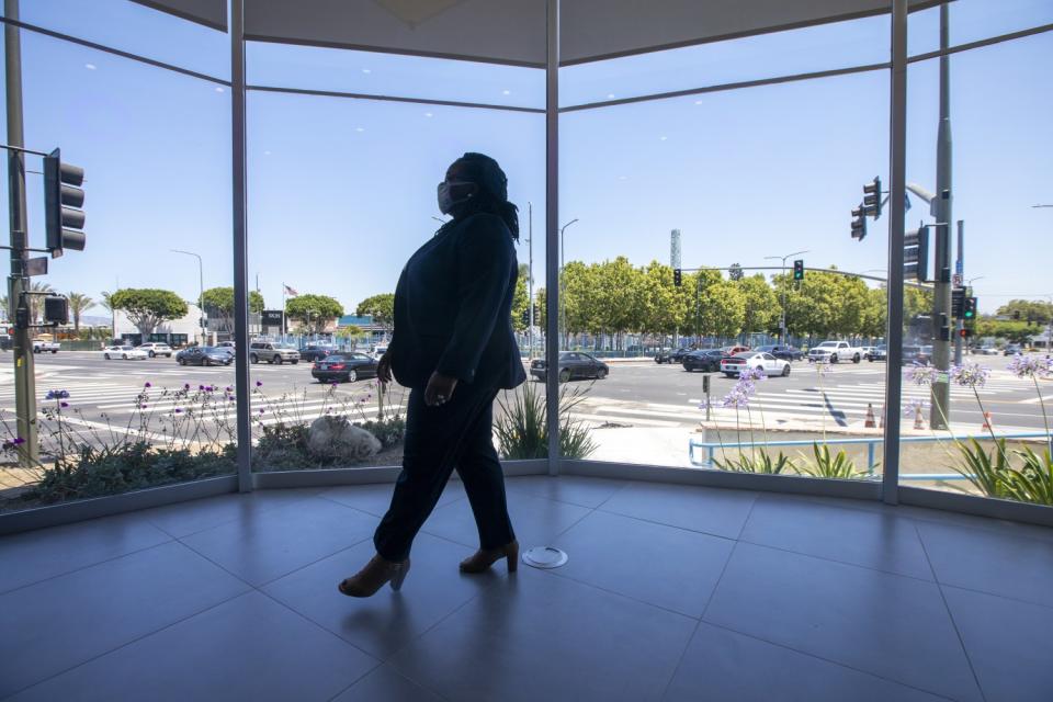 A person walks in front of a room with floor-to-ceiling windows that show a busy street.