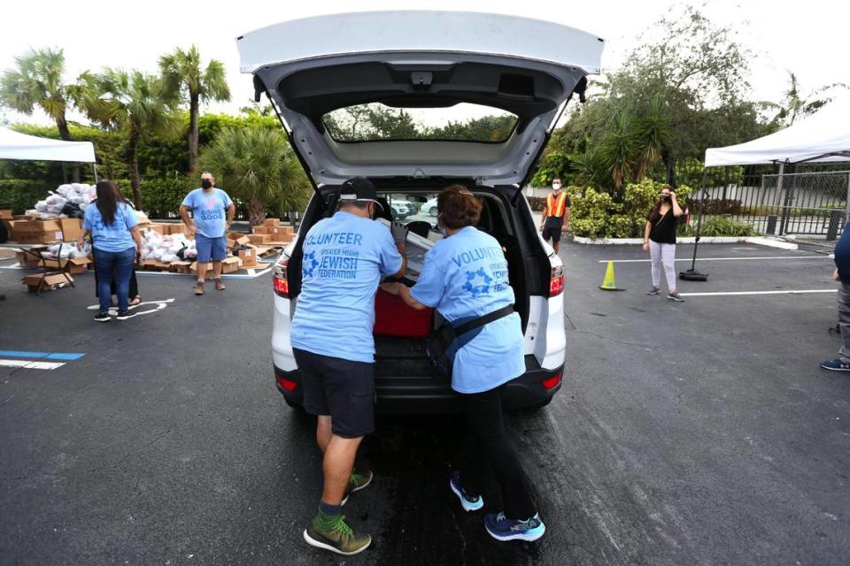 Volunteers load the trunk of an SUV with bags of food during a kosher food distribution event at the Greater Miami Jewish Federation parking lot in response to widespread economic hardship and food insecurity brought on by the COVID-19 pandemic, in Miami, Florida Friday, October 16, 2020.