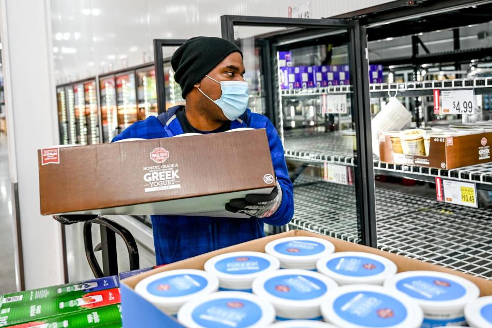 Aaron Dean stocks a refrigerator with yogurt prior to BJ's Wholesale Club's opening on Wednesday, Jan. 26, 2022, in Delta Township.