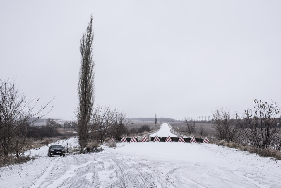 A car drives next to a main highway blocked at the Ukrainian side of the Ukraine - Russia border in Milove town, eastern Ukraine, Sunday, Dec. 2, 2018. On a map, Chertkovo and Milove are one village, crossed by Friendship of Peoples Street which got its name under the Soviet Union. On the streets in both places, people speak a mix of Russian and Ukrainian without turning choice of language into a political statement. (AP Photo/Evgeniy Maloletka)