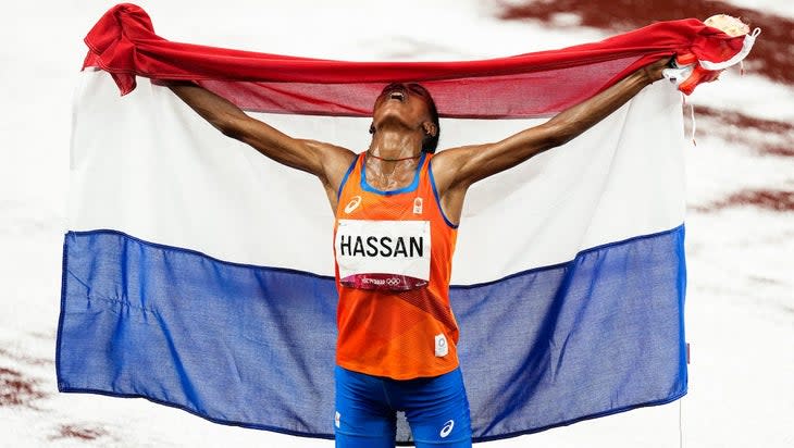 Sifan Hassan after winning gold in the 2020 Olympic 5,000m finals. She poses with a Dutch flag raised in victory.